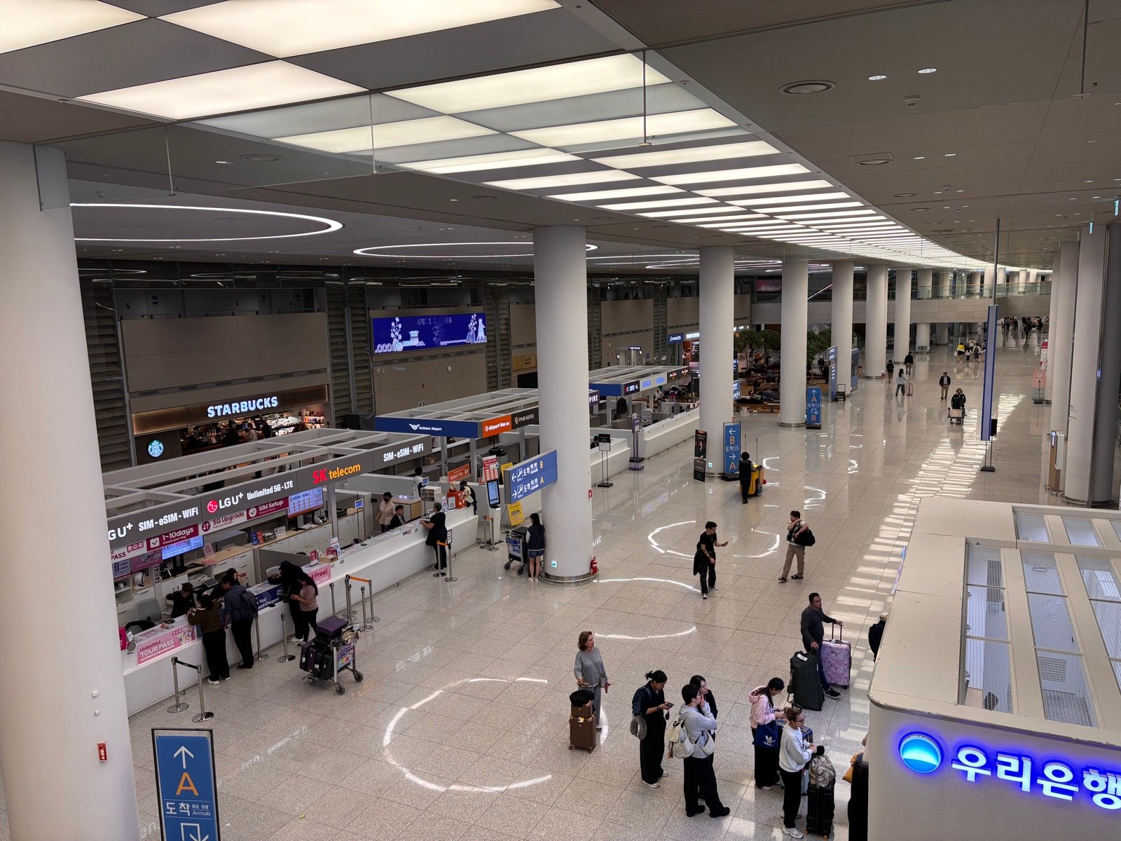 Arrivals hall at Incheon Airport Terminal 2 with SIM card counters and an Arrivals A sign