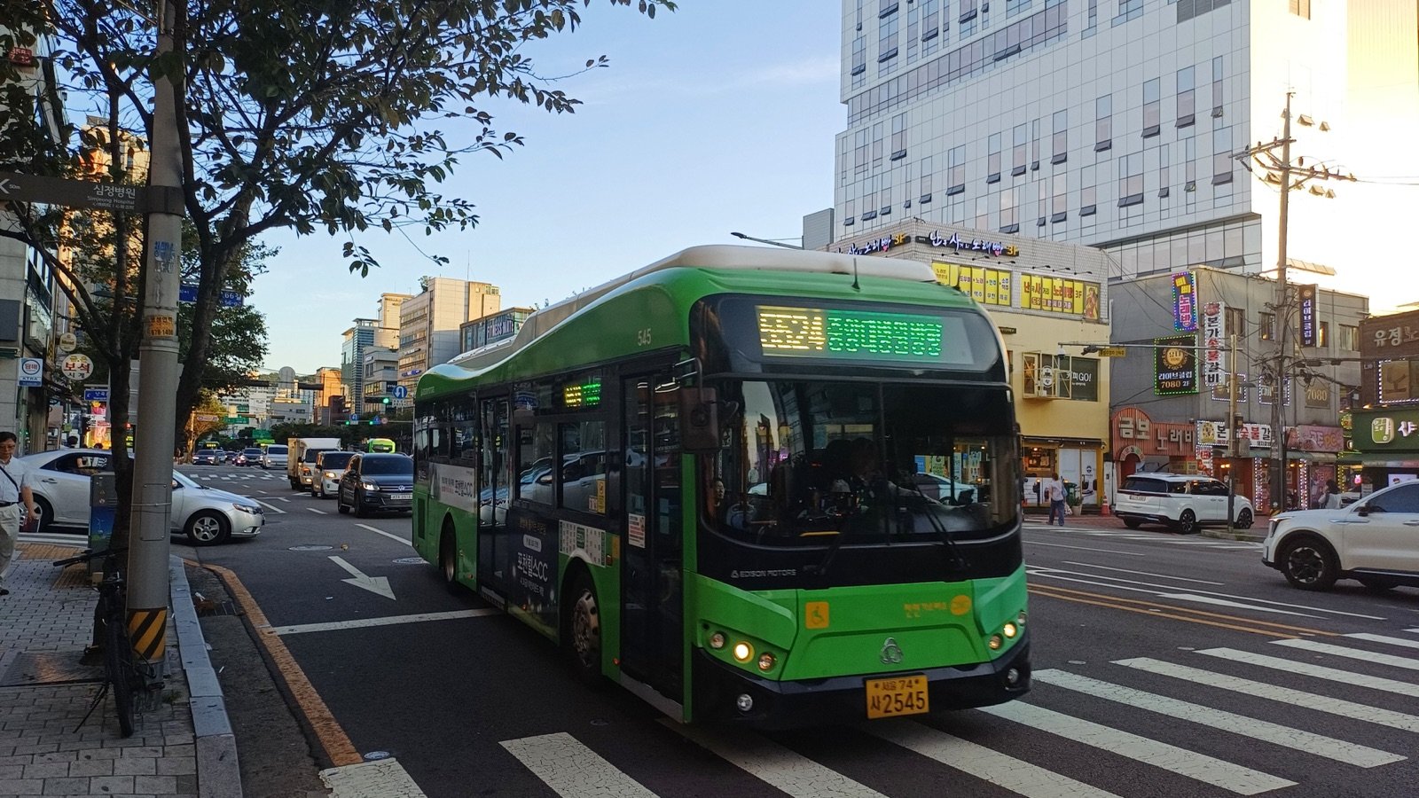 A green Seoul branch bus, route 5524, passing a crosswalk in warm evening light