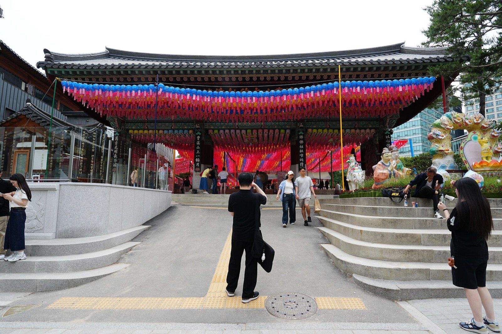 Jogyesa Temple main hall in Seoul with rows of colorful lanterns and visitors outside