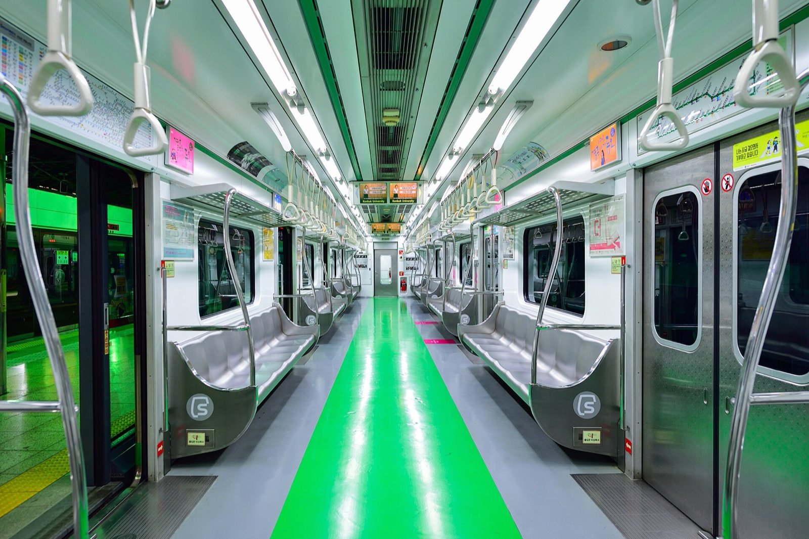 An empty Seoul Line 2 subway car with long bench seats and a green floor stripe