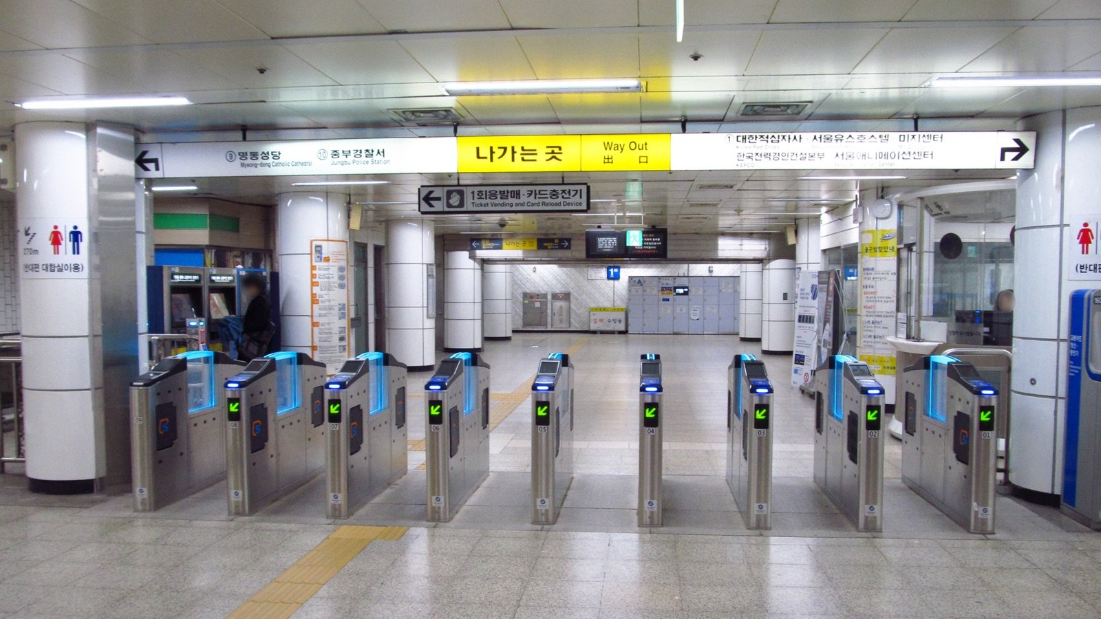 Empty ticket gates at Myeongdong Station with green arrows and bilingual Way Out signs above