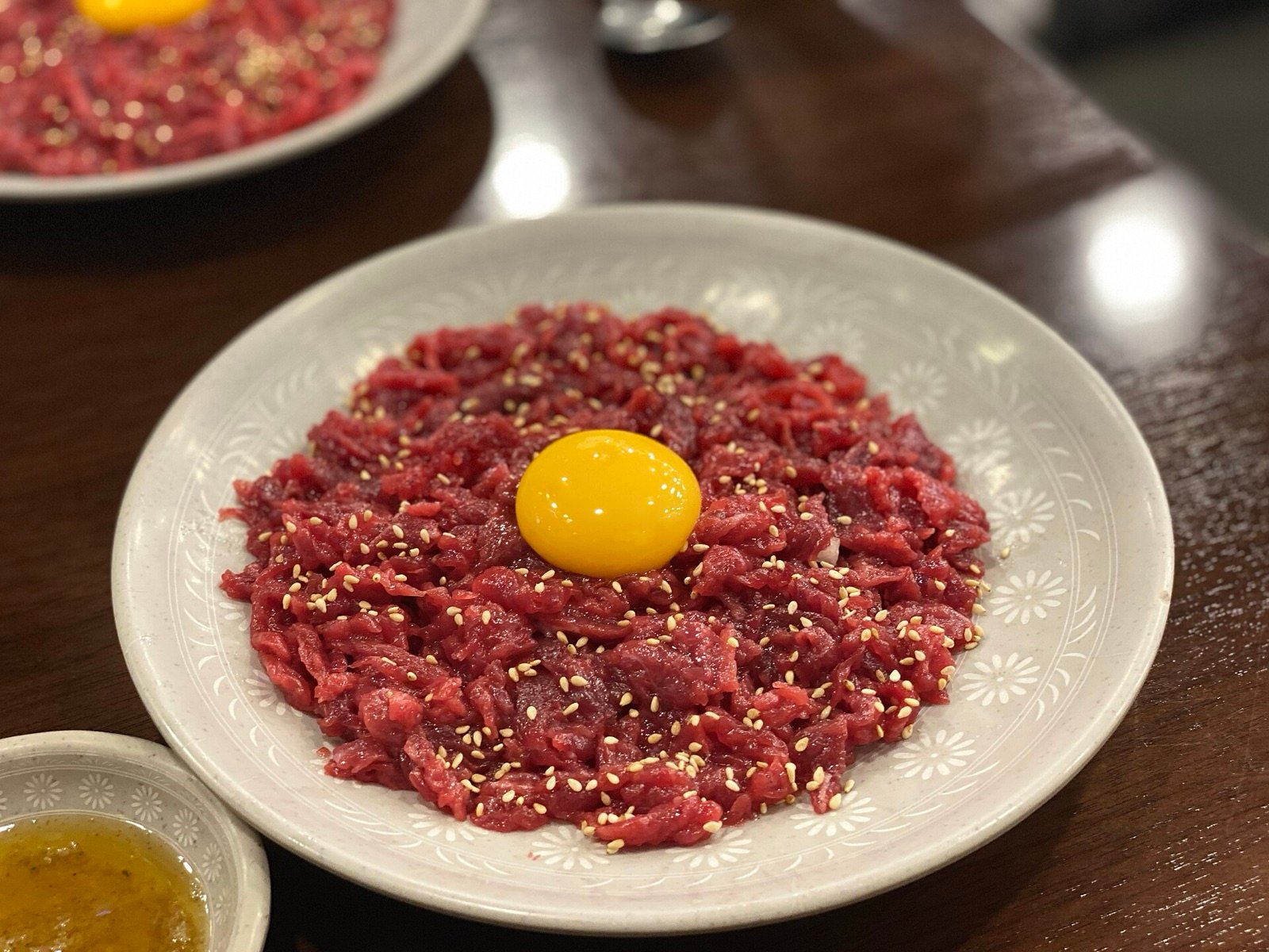 A plate of Korean raw beef yukhoe with an egg yolk and sesame seeds on top
