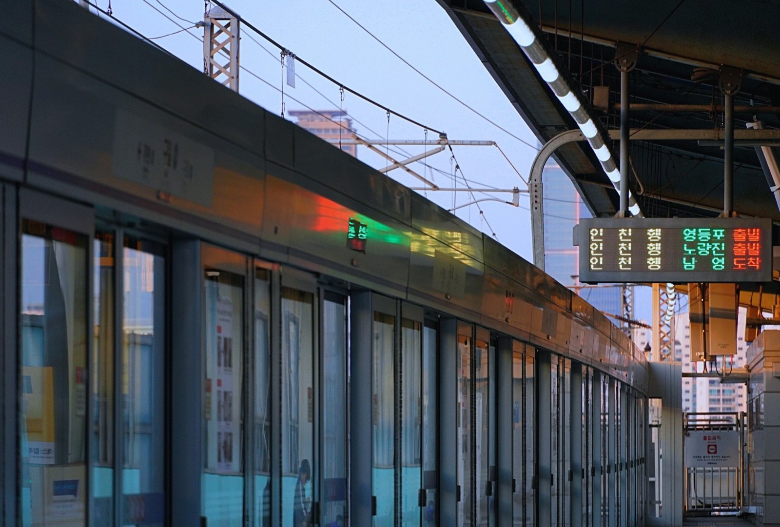 Platform screen doors and a train arrival board at Guil Station on Line 1 at dusk
