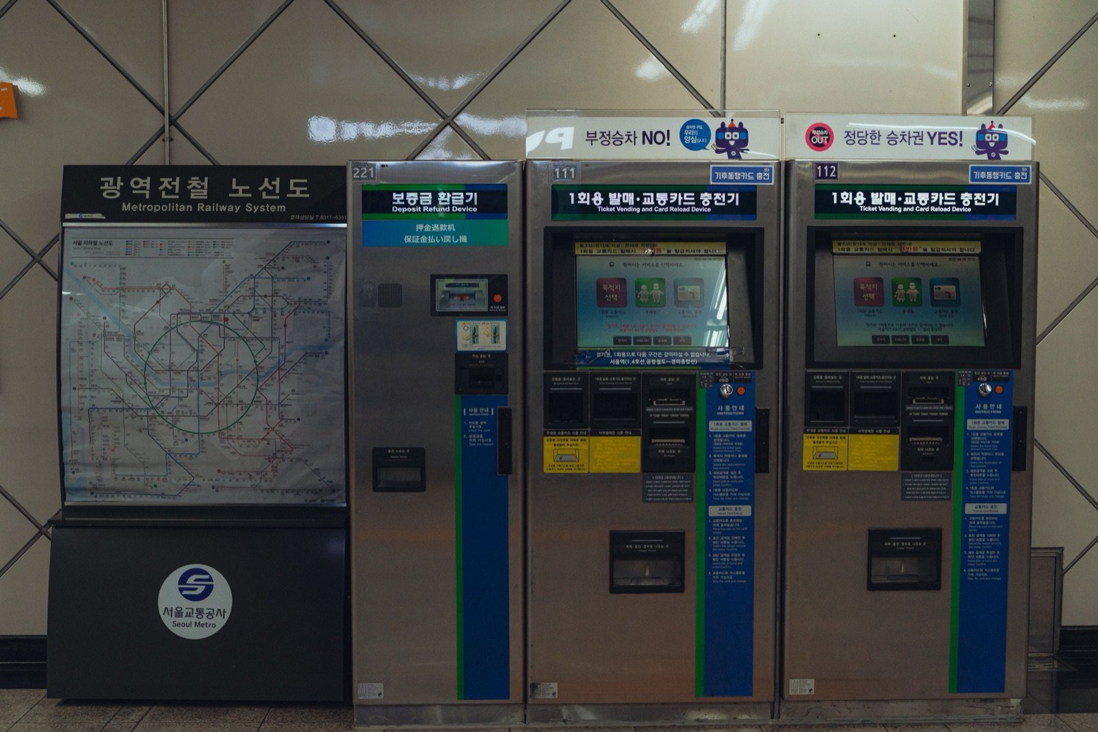 Ticket vending and card reload machines beside a metropolitan subway map in a Seoul Metro station
