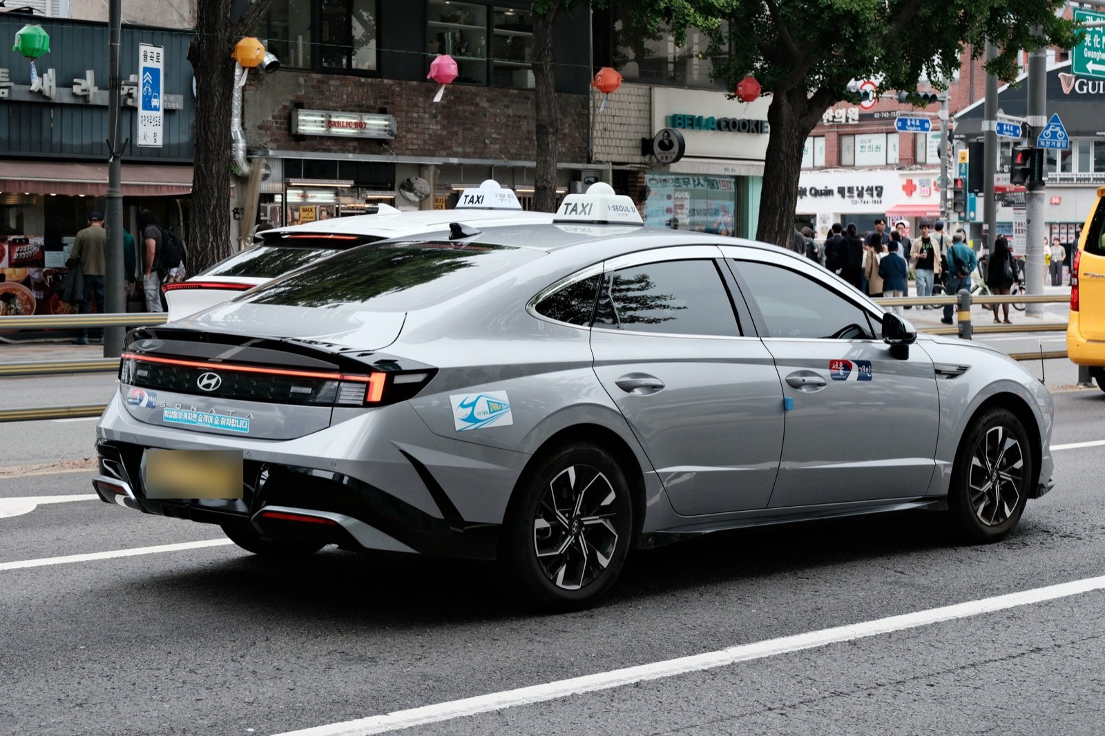A silver Seoul taxi with a rooftop TAXI sign on a city street